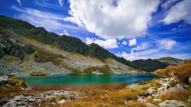 時間の経過 高い山の湖の幻想的なターコイズ色 太陽と交互に青い空とふわふわの雲 — ストック動画