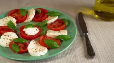 Bir erkek İtalyan caprese salatası, sulu taze domates, kremalı mozzarella, taze fesleğen ve ekstra saf zeytinyağı yer. Sağlıklı beslenme, organik gıda, sağlıklı yaşam tarzı konsepti. İtalya