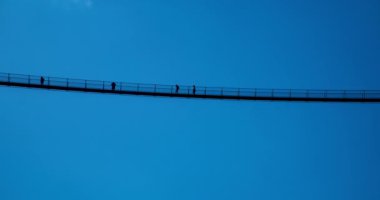 Zaman aşımı - Avrupa 'nın en yüksek Tibet Köprüsü' nde yürüyen insanların silueti İtalyan Alpleri Ponte nel cielo, Gökteki Köprü Val Tartano, Sondrio İtalya