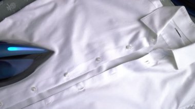 Evde ütü yapan bir adam, ev işi yapan çalışkan bir koca. Genç adam ütü yapıyor.