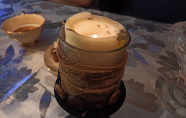 Masadaki el yapımı şamdanda bir mum yanıyor. 