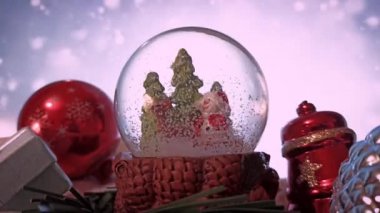 Yılbaşı ve Noel için kırmızı süslemeler. Beyaz kar yağan arka planda Noel Baba ve geyik olan kar küresi. 