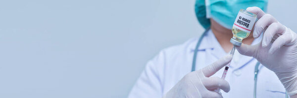 Doctor holding syringe and Covid-19 vaccine vial-Medicine, pharmaceutical research and health care concept, copy space