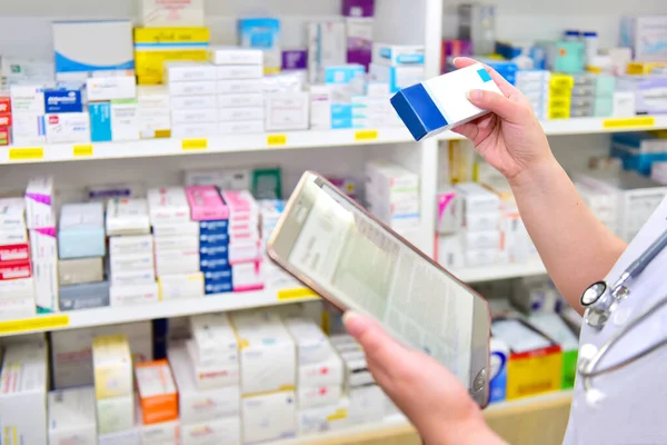 Pharmacist holding medicine box and touch pad for search bar on display in pharmacy drugstore shelves background. Online medical concept.