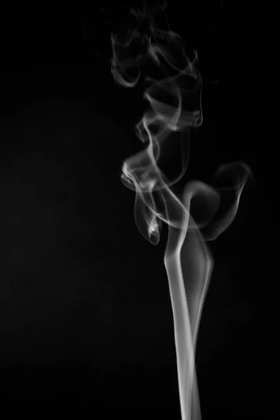 A black and white swirling, ascending smoke pattern on a black background, photo could be used as a background, smoke texture, abstract, or general stock photography.