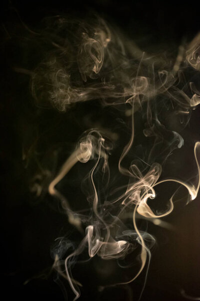 Golden yellow swirling, ascending smoke pattern on a black background, photo could be used as a background, smoke texture, abstract, or general stock photography.