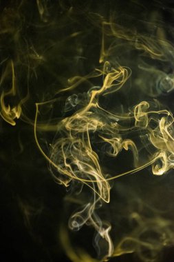 Sarı altın kıvrımlı, yükselen bir duman deseni siyah arka planda, fotoğraf arka plan, duman dokusu, soyut veya genel stok fotoğrafçılığı olarak kullanılabilir..