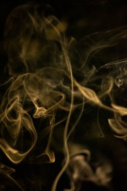 Siyah arka planda altın sarısı, kıvrımlı, yükselen, duman deseni, fotoğraf arka plan, duman dokusu veya soyut veya genel stok fotoğrafçılığı olarak kullanılabilir..