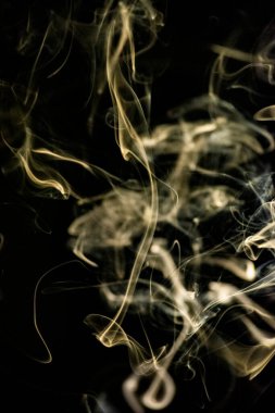 Siyah arka planda altın sarısı, kıvrımlı, yükselen, duman deseni, fotoğraf arka plan, duman dokusu veya soyut veya genel stok fotoğrafçılığı olarak kullanılabilir..