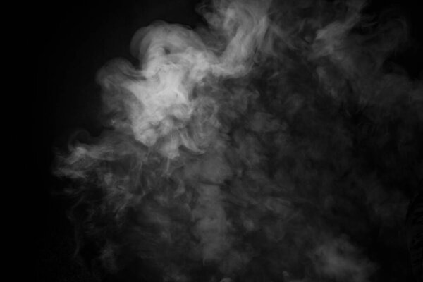 A white smoke cloud with yellowish hue on a black background, photo could be used as a background, smoke texture or abstract - stock Photography