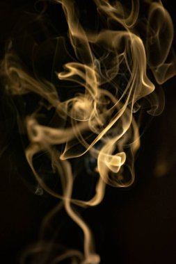 Siyah arka planda altın sarısı, kıvrımlı, yükselen bir duman deseni, fotoğraf arka plan, duman dokusu veya soyut veya genel stok fotoğrafçılığı olarak kullanılabilir..