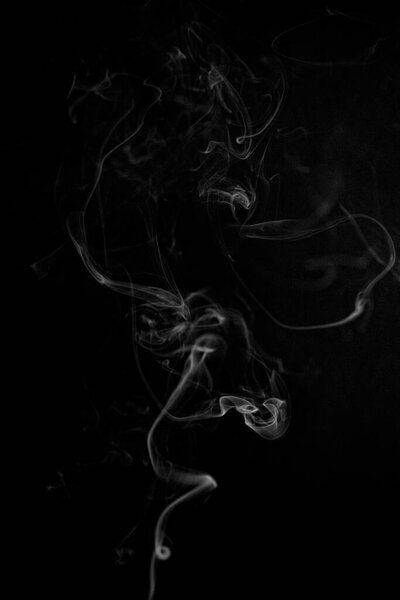 A white swirling ascending smoke pattern on a black background, photo could be used as a background, smoke texture or abstract, or general stock photography.