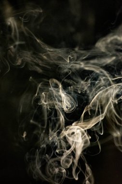 Siyah arka planda sarımsı bir tona sahip kıvrımlı, yükselen bir duman deseni, fotoğraf arka plan, duman dokusu veya genel stok fotoğrafçılığı olarak kullanılabilir..