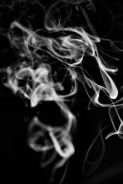 Siyah arkaplanda beyaz, girdap şeklinde yükselen bir duman deseni, arka plan, duman dokusu veya soyut veya genel stok fotoğrafçılığı olarak kullanılabilir..