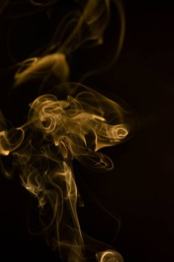 Siyah arka planda altın sarısı kıvrımlı, yükselen duman deseni, fotoğraf arka plan, duman dokusu, soyut veya genel stok fotoğrafçılığı olarak kullanılabilir.