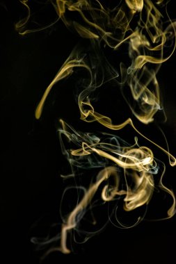 Golden yellow swirling, ascending smoke pattern on a black background, photo could be used as a background, smoke texture, abstract, or general stock photography. clipart