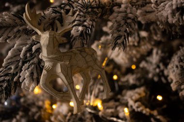 Karla kaplı bir çam dalında geyik şeklinde Noel ağacı oyuncağı.