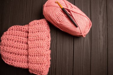 Pembe iplik ve siyah bir masaya örgü örmek için sıcak örgü örgü şapka..