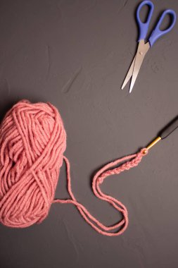 Gri arkaplanda makas ve kancalı pembe iplik..