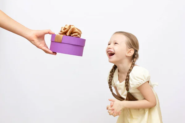 Adorável menina surpresa com caixa de presente roxo presente no fundo — Fotografia de Stock
