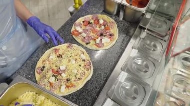 Şef pizzayı çabucak elleriyle çürütür ve pişirmek için hazırlar. Üst görünüm.