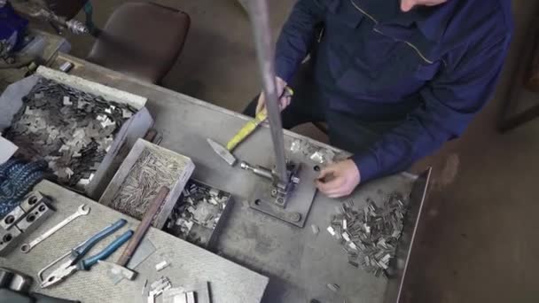 Arbetaren skapar en metallprodukt på fabriken med hjälp av en speciell maskin. Handgjord i produktion. Hammarslag. Människan gör stål detalj. — Stockvideo