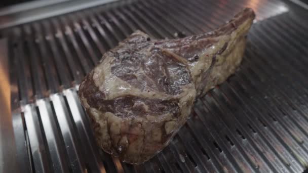Velký tomahawk steak se smaží na grilu. Připravuje se šťavnatý kus masa. Mastné nevyžádané jídlo. — Stock video