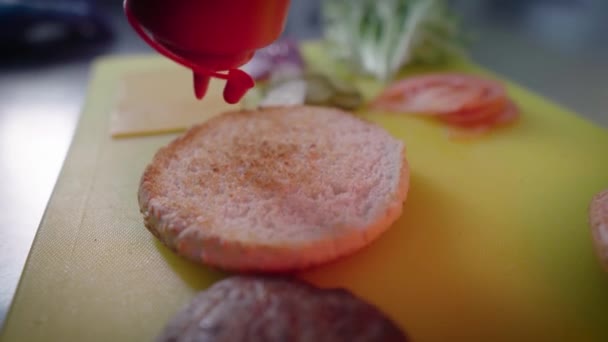 Cocine untar la salsa en un bollo de hamburguesa con botella. Cocinar comida callejera. Encima de hamburguesa. — Vídeos de Stock