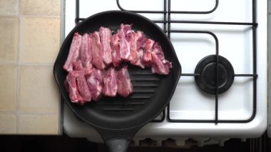 Mutfaktaki normal bir sobanın üstünde gerçek bir ev yemeği. Küçük et parçaları tavaya elle konur. Üst görünüm. 