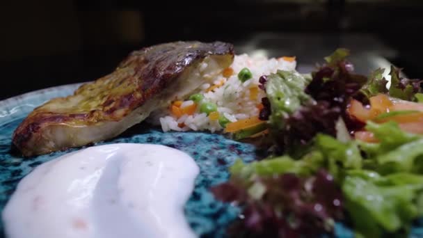 Smażone ryby z ryżem i warzywami. Obracające się jedzenie. Dietetyczne zdrowe jedzenie. Pyszna kuchnia z bliska. Prezentacja dania z restauracji w pięknym, stylowym talerzu. Pokazywanie kulinarnego arcydzieła. — Wideo stockowe