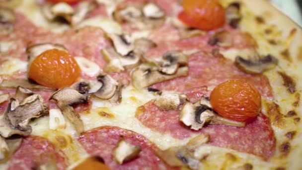 新鲜的圆形披萨，西红柿和莫扎拉奶酪放在桌子上。服装店的饭菜很好吃.从比萨饼店的宏观观点看快餐背景.轮换的食物. — 图库视频影像