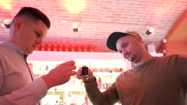 Deux jeunes hommes boivent de l'alcool fort. Dégustation de boissons alcoolisées. Degustation sur le bar. Grimace du visage. — Video