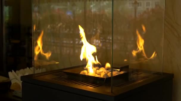 Gas glass fireplace with stones. Bright glow and comfort in house in winter. Modern heating system. Contemporary mount biofuel on ethanol fireplace fireplace close-up. — ストック動画