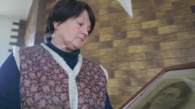 Yaşlı bir kadın, atasının eski bir portresini tutarken ve ona bakarken üzülüyor. Yaşlı kadın üzgün görünüyor ve evde dururken nostalji yapıyor. Duygular, duygular ve anılar kavramı