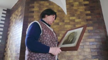 60 'lı yaşlardaki yaşlı kadınlar, eski bir atalarının fotoğraflarıyla konuşurlar. Rahat evlerinde nostaljik hafızaları olan, rahat, yaşlı ve buruşuk elleri olan bir kadın. Biyografi, anılar veya tarih kavramı