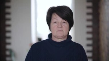 Yüzünde kırışıklıklar olan, kameraya bakıp iç çeken düşünceli yaşlı bir kadının portresi. Tutku kavramı. Evde tek başına duran üzgün bir kadın model. Büyük hanım..