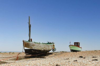 Kent 'teki Dungeness Burnu' nun geniş kiremitli sahillerinde birçok eski, yıpranmış balıkçı tekneleri var..