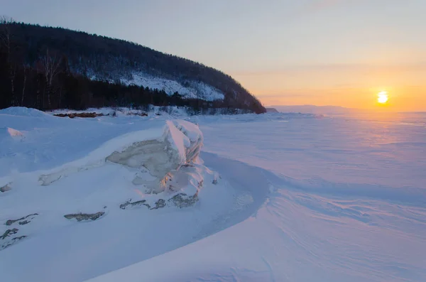 Das Ufer des Baikalsees liegt im Schnee. Ein gefrorener See bei Sonnenuntergang. — Stockfoto