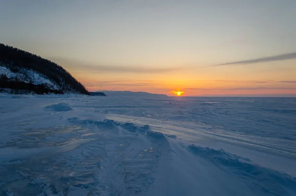 The shore of Lake Baikal is in the snow. A frozen lake at sunset. — Stock fotografie