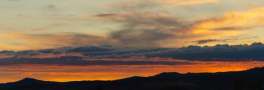 Gün batımında turuncu gökyüzü. Güneş dağların ardında batıyor..