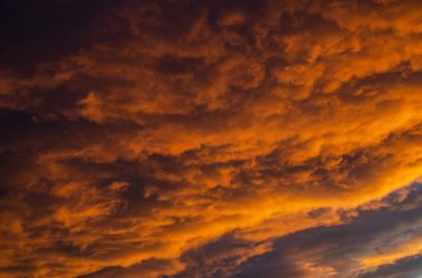 Bereketli, ağır bulutlar, güneş batarken turuncuya boyanmış. Doku.