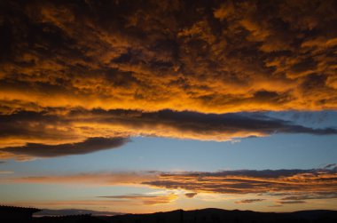 Bereketli, ağır bulutlar, güneş batarken turuncuya boyanmış. Doku.