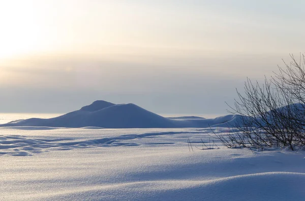 Schneeverwehungen mit den Strahlen der untergehenden Sonne. Winterlandschaft. — Stockfoto