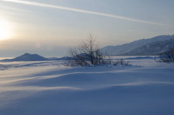 Schneeverwehungen mit den Strahlen der untergehenden Sonne. Winterlandschaft. — Stockfoto