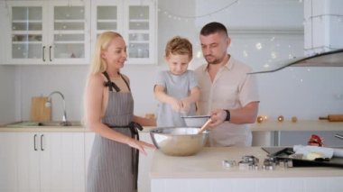 Mutlu aile anne, baba ve oğul sıcak mutfakta Noel kurabiyesi pişiriyor..