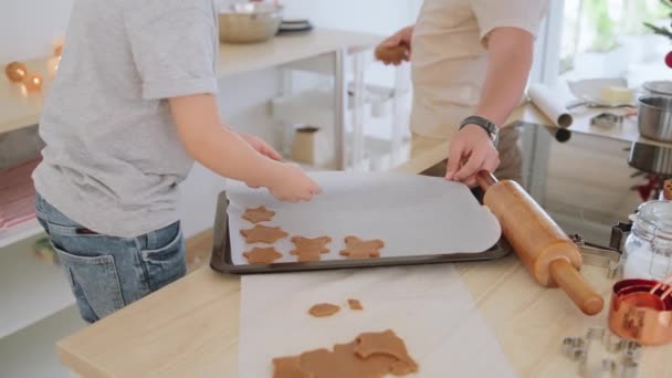 Рука маленького хлопчика розміщує мотив у формі тіста для печива на випічці з батьком . — стокове відео