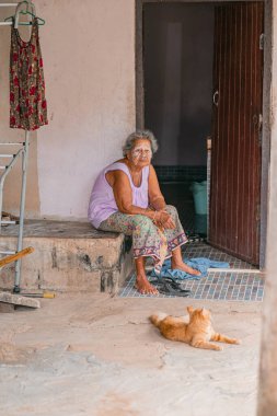 Yüzünde Thanaka macunu olan yaşlı kadın Tayland 'da evinin kapısında oturuyor.