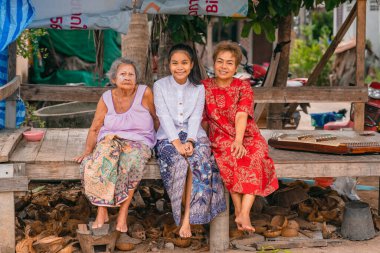 Mutlu Asyalı kuşaklar boyunca torununun büyükannesi dışarıda oturuyor.