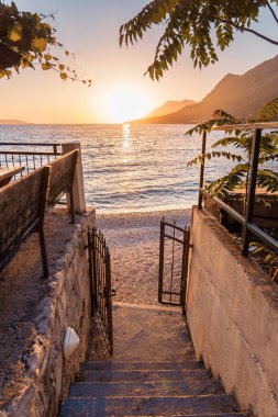 Gün batımında güneş ışığı ve mavi denizin olduğu güzel bir sahil.