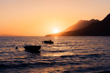 Günbatımında deniz, suda kayıklar. 